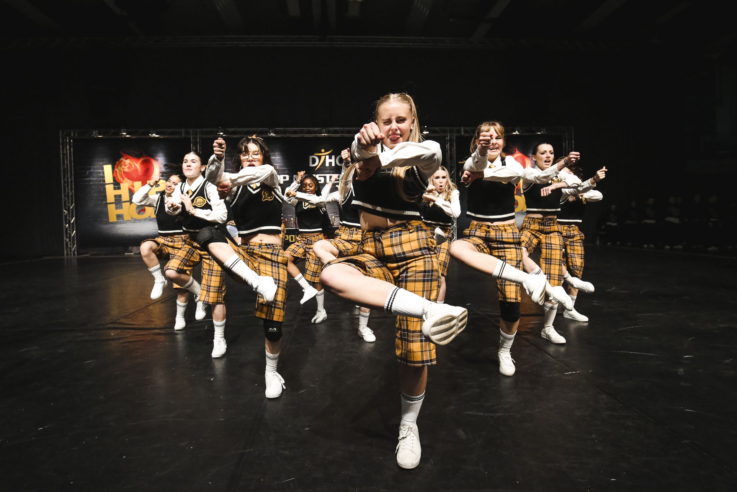 Tanzcrew in karierten Kostümen bei einer dynamischen Choreografie
